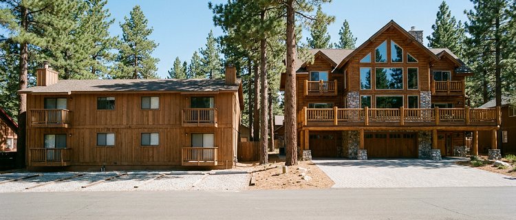 A two-story Big Bear condo building beside a large six-bedroom log lodge, showing how cabin size in Big Bear shapes the guest and the revenue